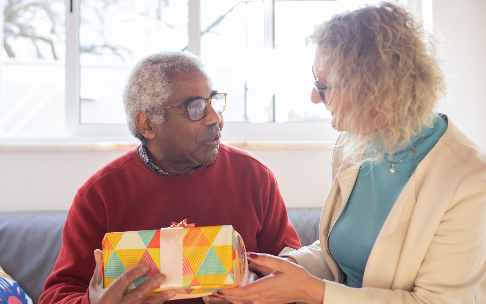 An older man and a carer sitting together in a bright living room