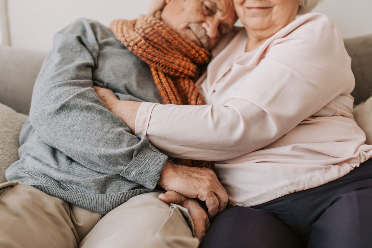 An elderly couple sitting close together on a sofa
