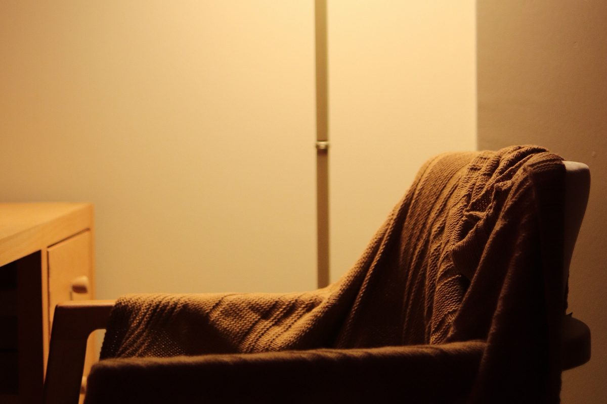A warmly lit lamp beside an armchair in a quiet room at night